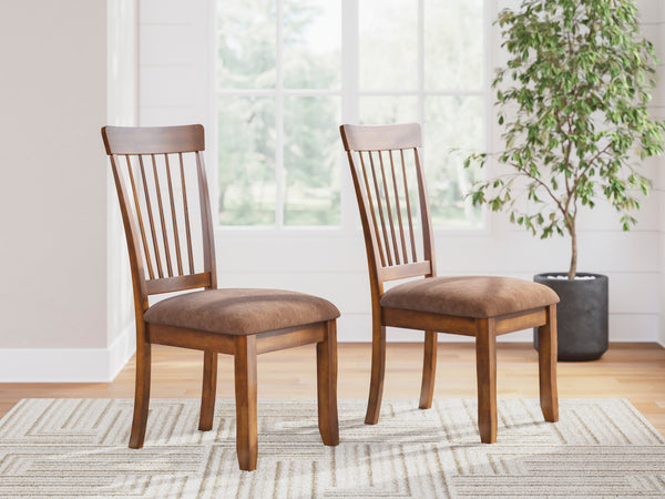 Two wooden chairs with brown cushions in a room with a plant and window.